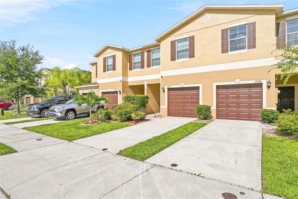 An exterior view of a two-story tan townhouse with a two-car garage and driveway — 12911 DREAM CATCHER WAY, RIVERVIEW, FL