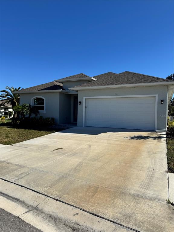 A single-story house with a two-car garage and a concrete driveway under a clear sky — 720 REDBUD COURT, ENGLEWOOD, FL