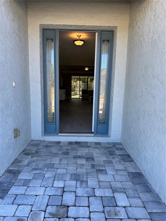 A front entryway with a blue door, glass sidelights, and a gray paver patio — 720 REDBUD COURT, ENGLEWOOD, FL