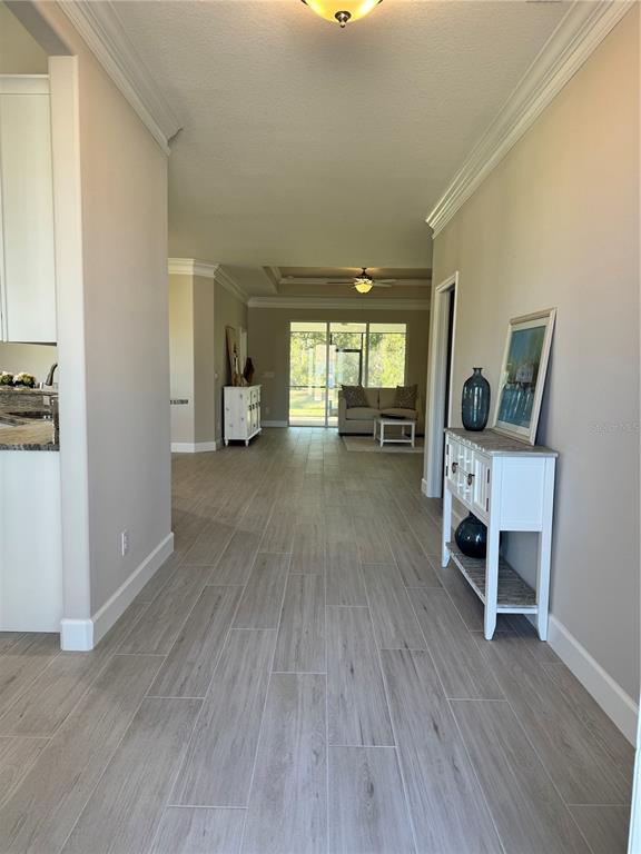 A hallway with light wood-look tile flooring leads to a living area with glass doors — 720 REDBUD COURT, ENGLEWOOD, FL