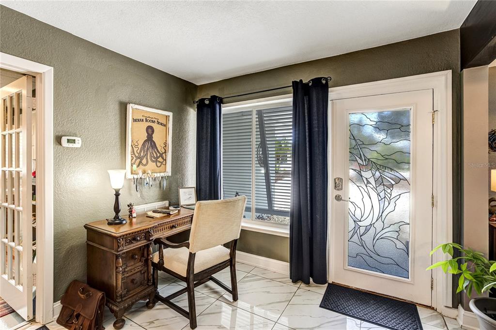 A home office with a wooden desk, chair, window, and a glass-paneled door — 326 MEHLENBACHER ROAD, BELLEAIR, FL