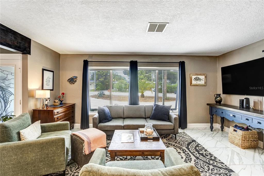 A living room features a gray sofa, two green armchairs, a coffee table, and tile flooring — 326 MEHLENBACHER ROAD, BELLEAIR, FL