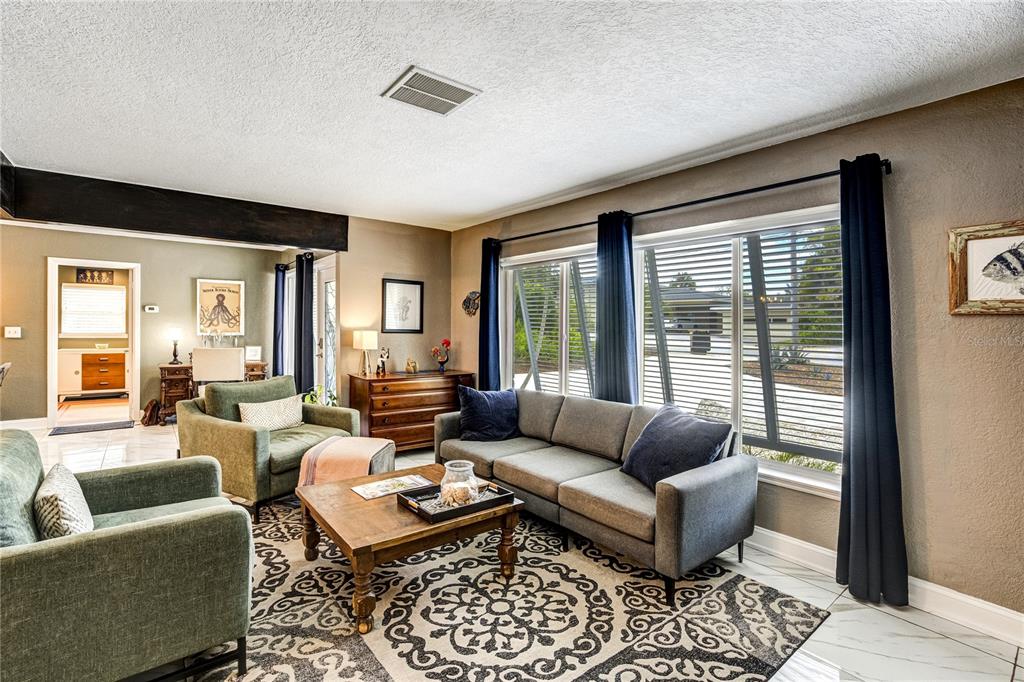 A living room features a gray sofa, two green armchairs, and a patterned area rug — 326 MEHLENBACHER ROAD, BELLEAIR, FL