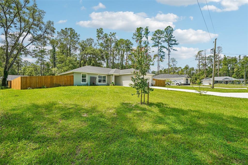 A gray single-story house with a wooden fence sits on a large grassy lot — 9971 N BAMBOO WAY, DUNNELLON, FL
