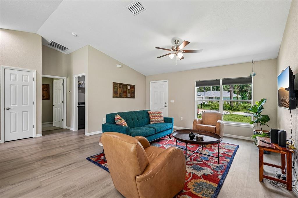 A living room features a teal sofa, two leather armchairs, and a patterned area rug — 9971 N BAMBOO WAY, DUNNELLON, FL