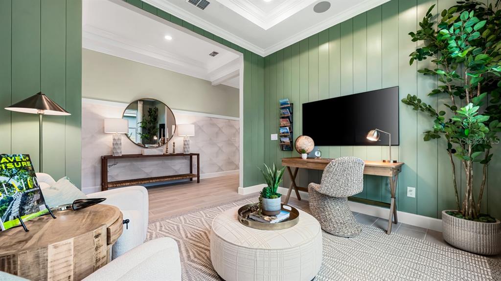 A home office features green vertical shiplap walls, a desk, a television, and an ottoman — 7907 CORAL SEA LANE, PALMETTO, FL