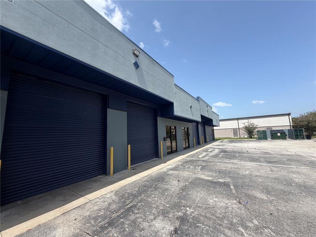 An exterior view of a commercial building with multiple roll-up doors and a parking lot — 1424 HAMLIN AVENUE UNIT H, ST CLOUD, FL