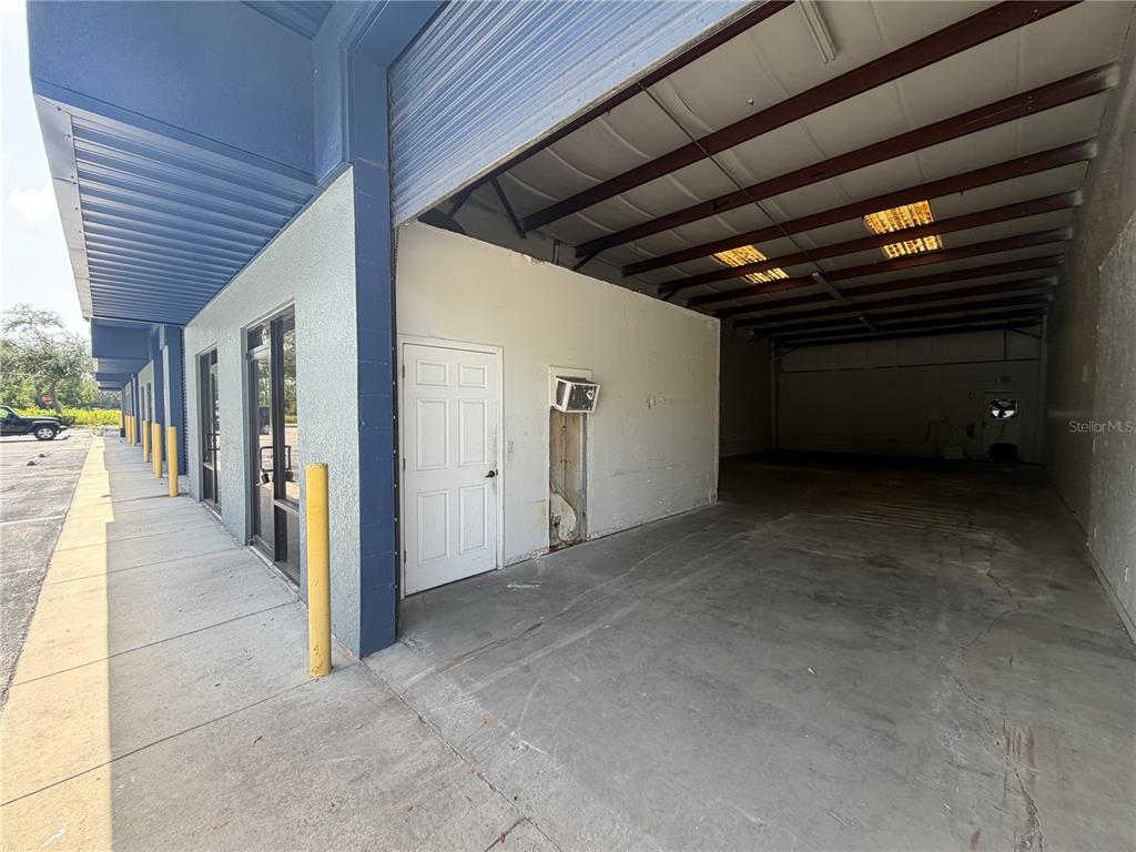 An exterior view shows a commercial building with a concrete parking area and warehouse bay — 1424 HAMLIN AVENUE UNIT H, ST CLOUD, FL