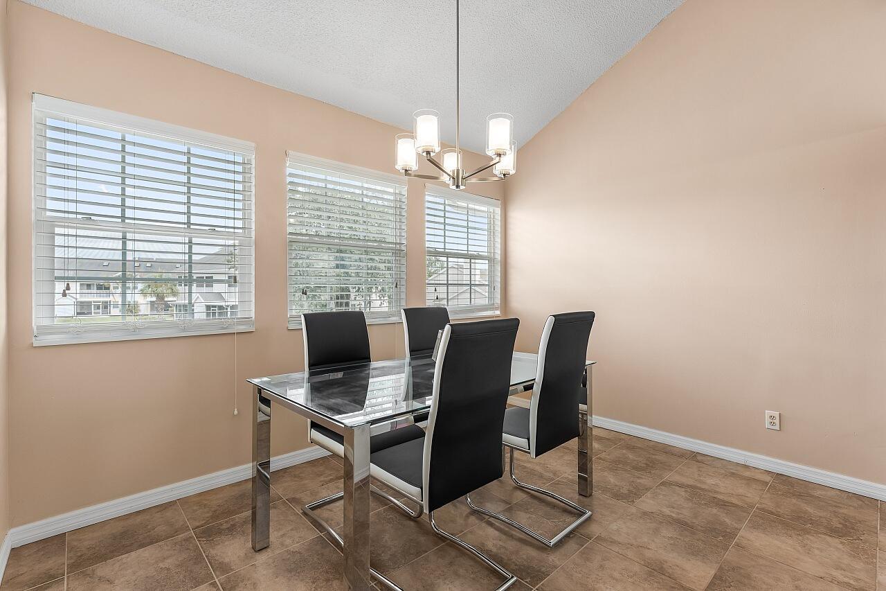 A dining room with a glass table, four black chairs, tile flooring, and three windows — 1965 Westminster Circle # 6, Vero Beach FL 32966, VERO BEACH, FL