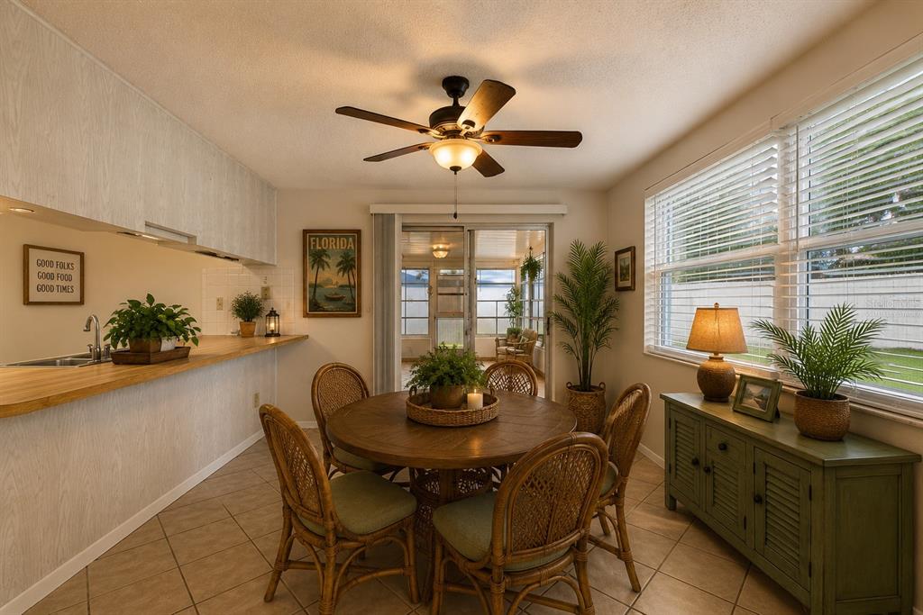 A dining area features a round wooden table, wicker chairs, and a green sideboard — 7203 CHERRY LAUREL DRIVE, PORT RICHEY, FL