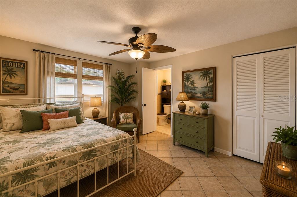 A bedroom features a white metal bed, a green dresser, and a ceiling fan — 7203 CHERRY LAUREL DRIVE, PORT RICHEY, FL