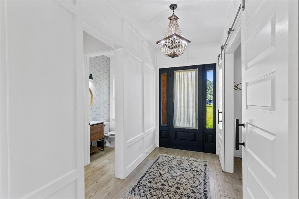 An entryway features white board-and-batten walls, a beaded chandelier, and a black front door — 19110 SHELDON STREET, ORLANDO, FL