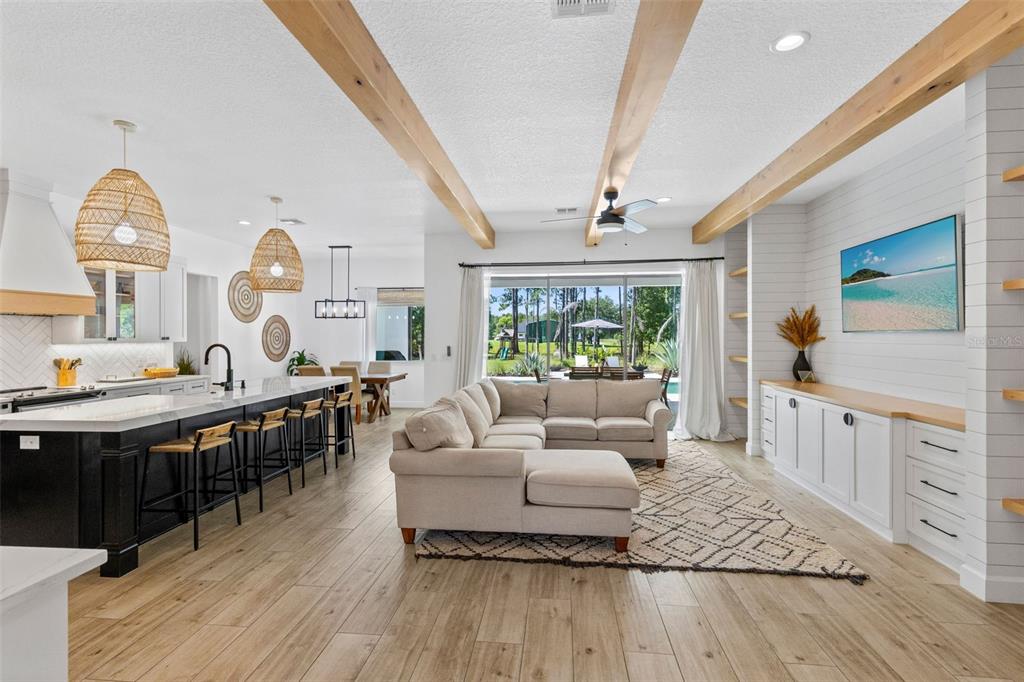 An open-concept living room and kitchen feature wood-look tile floors, exposed ceiling beams, and cabinetry — 19110 SHELDON STREET, ORLANDO, FL