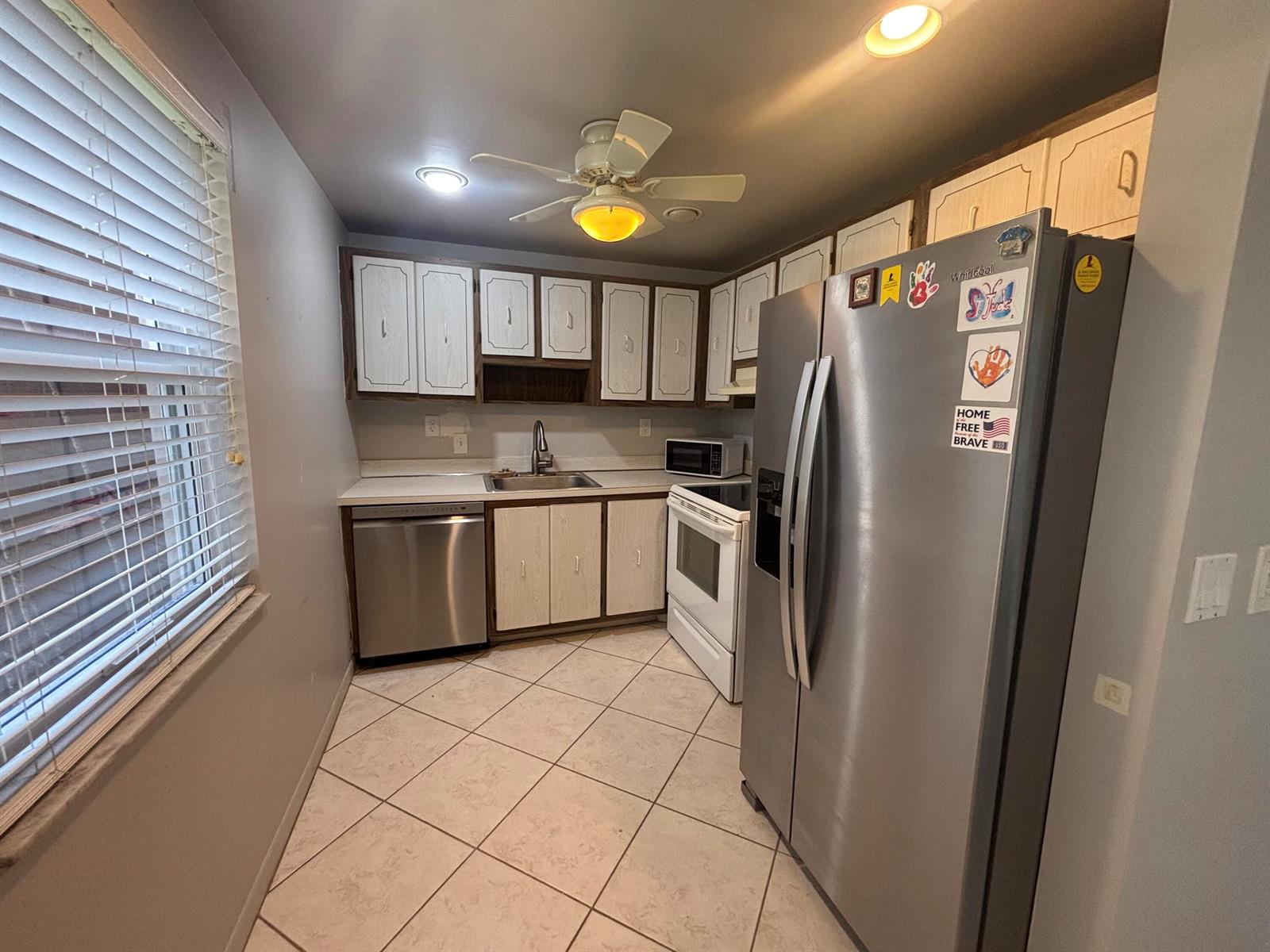 A kitchen features stainless steel appliances, white cabinets, a tiled floor, and a ceiling fan — 341 Piedmont # H, Delray Beach FL 33484, DELRAY BEACH, FL