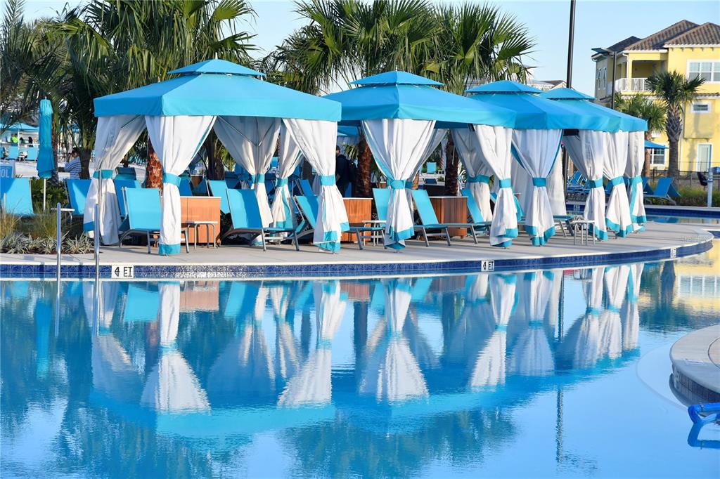 A swimming pool with blue cabanas and lounge chairs on a paved deck — 2956 ON THE ROCKS, KISSIMMEE, FL