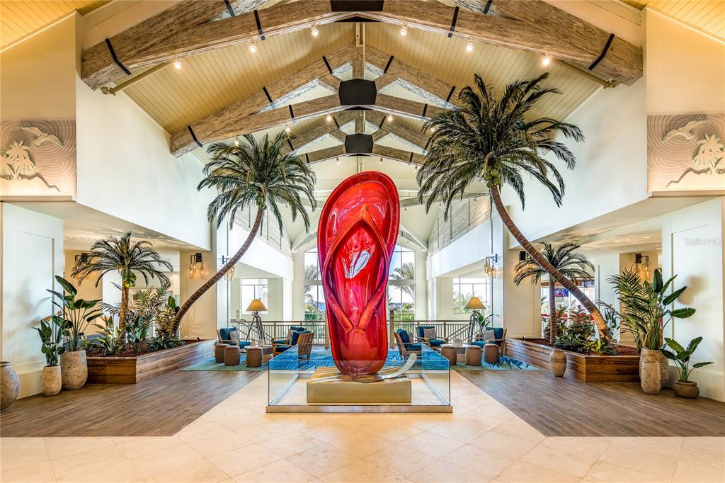 A large red flip-flop sculpture stands in a bright lobby with palm trees and beams — 2956 ON THE ROCKS, KISSIMMEE, FL