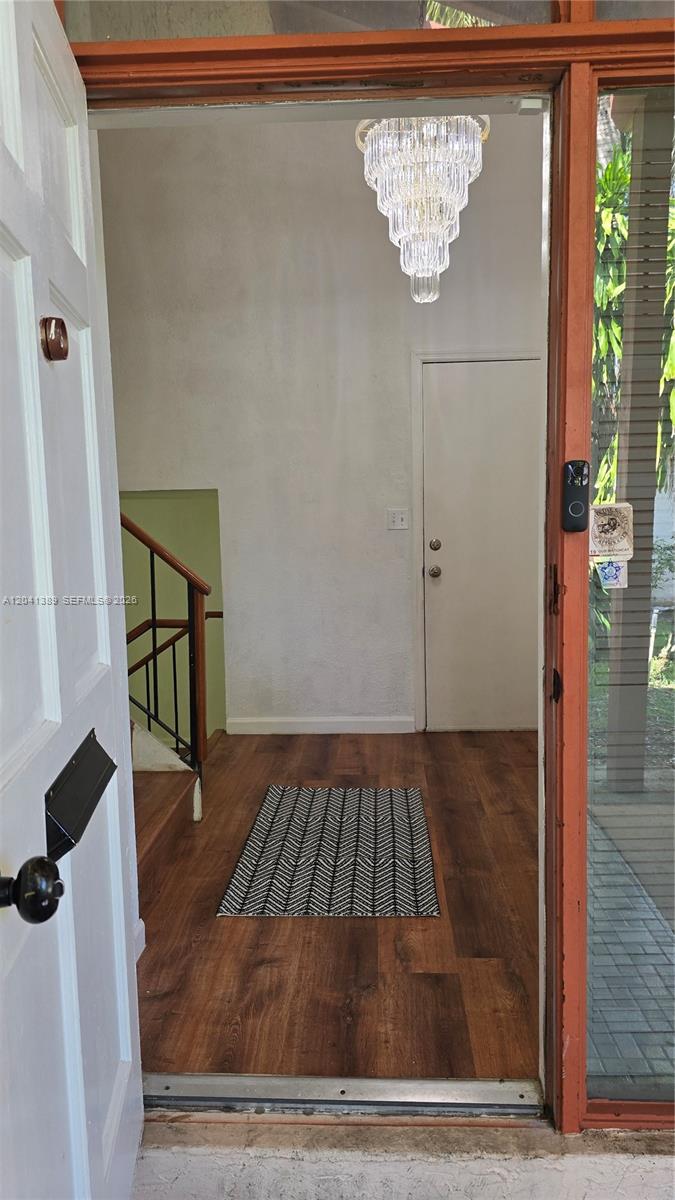 An entryway features wood-look flooring, a crystal chandelier, and a staircase with a wooden railing — 3412 Spring Bluff Pl # 43, Lauderhill FL 33319, LAUDERHILL, FL