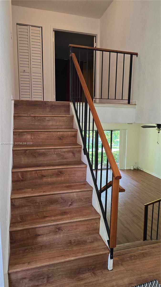 A wooden staircase with a black metal railing leads to an upper landing — 3412 Spring Bluff Pl # 43, Lauderhill FL 33319, LAUDERHILL, FL