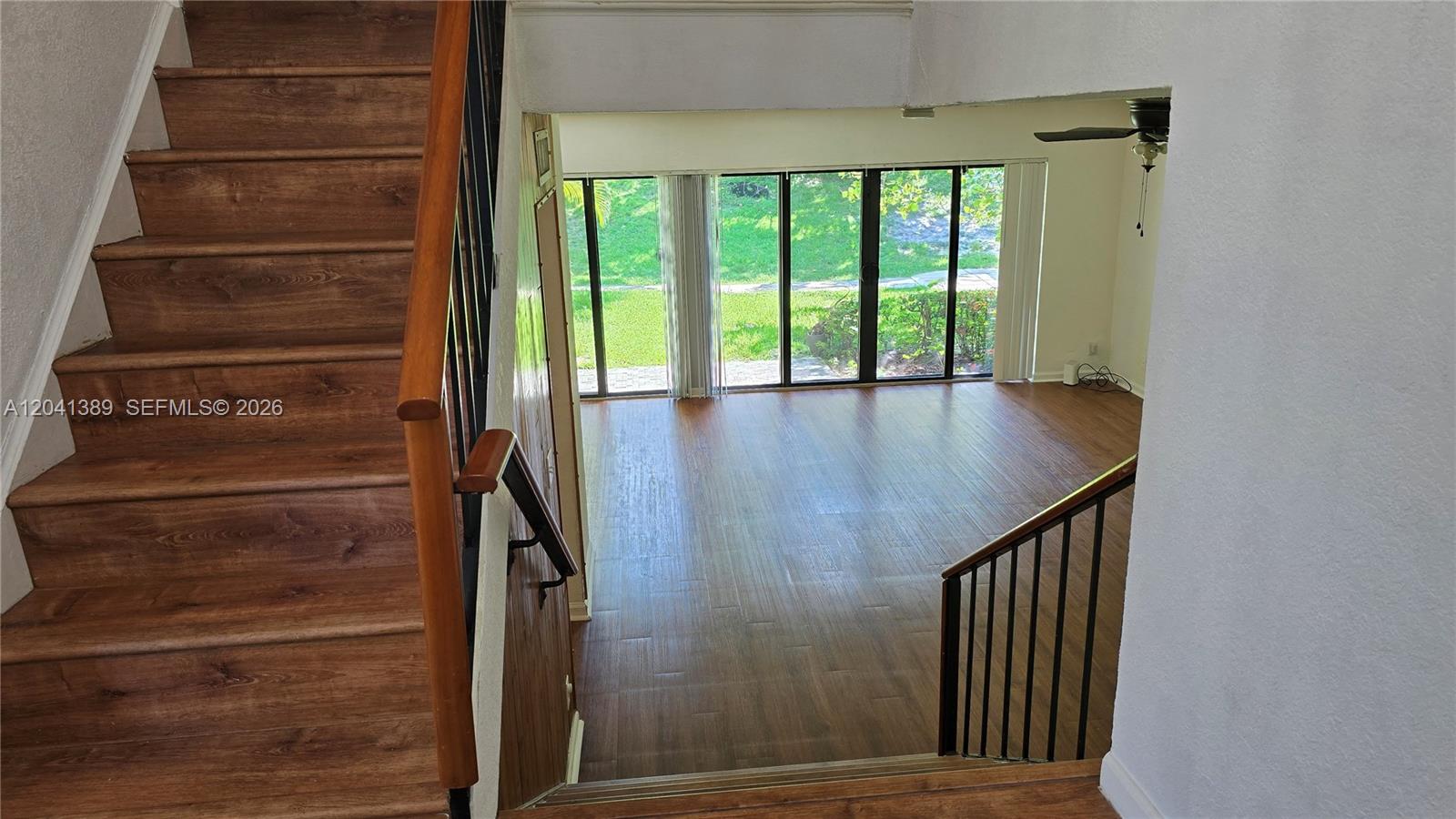 A staircase with wood-look flooring leads down to a living area with large glass doors — 3412 Spring Bluff Pl # 43, Lauderhill FL 33319, LAUDERHILL, FL