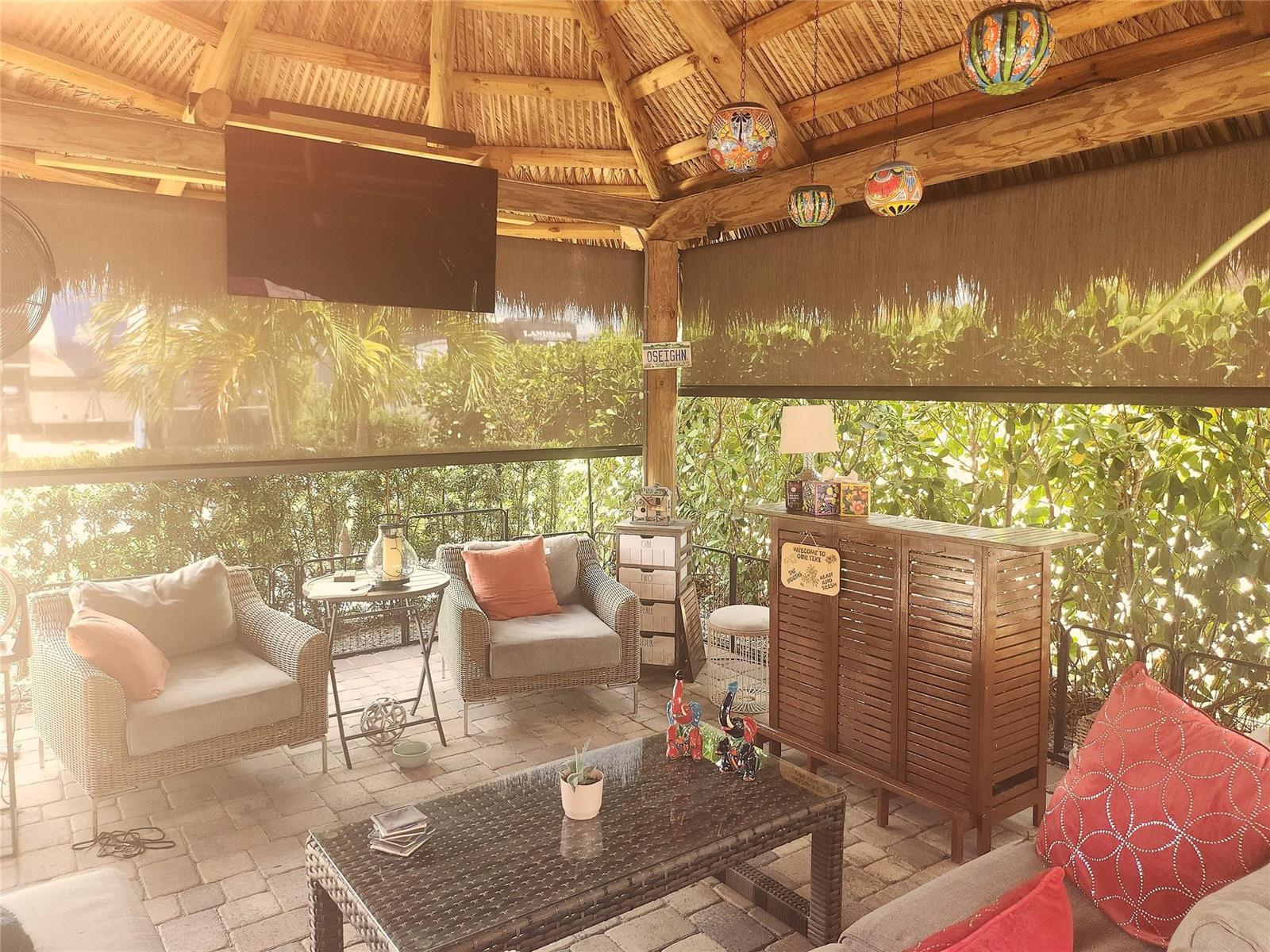 A covered outdoor patio features wicker furniture, a bar, and hanging decorative lanterns — 622 SW 42nd Cove, Okeechobee FL 34974, OKEECHOBEE, FL