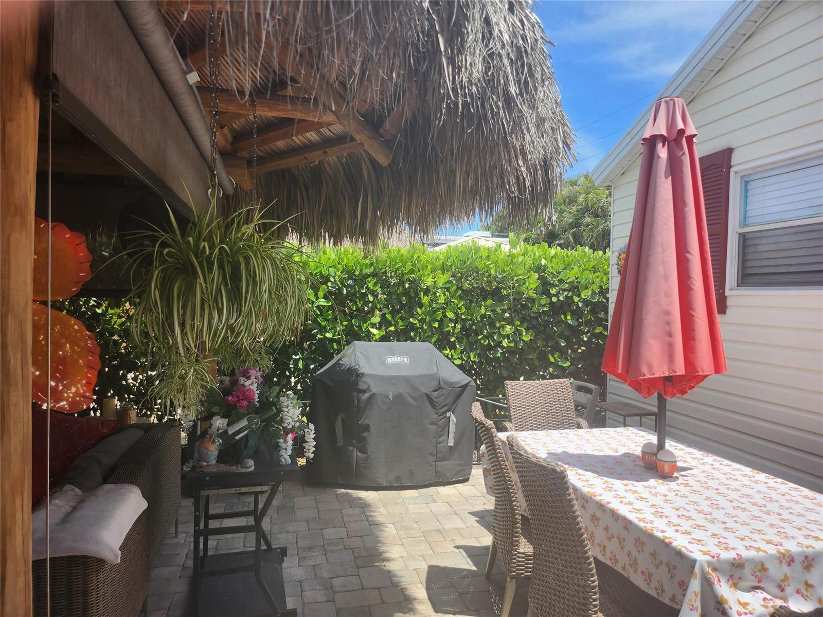A patio features a thatched roof, a covered grill, and a dining table with an umbrella — 622 SW 42nd Cove, Okeechobee FL 34974, OKEECHOBEE, FL