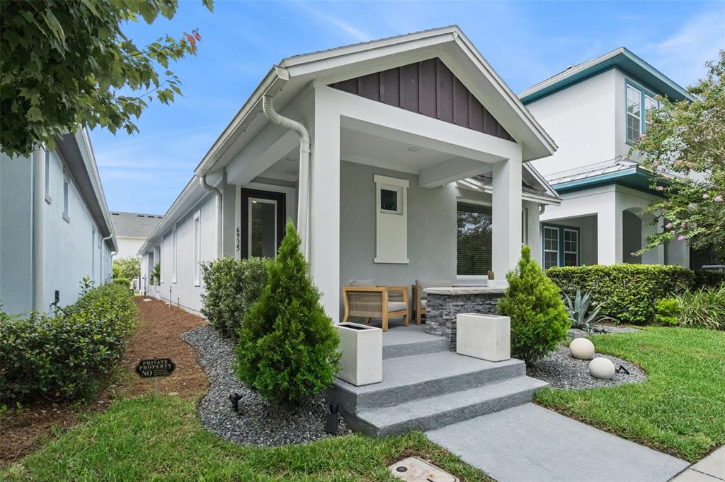 A gray house with a covered front porch, stone accents, and a small landscaped yard — 6935 HIGGS ALLEY, ORLANDO, FL