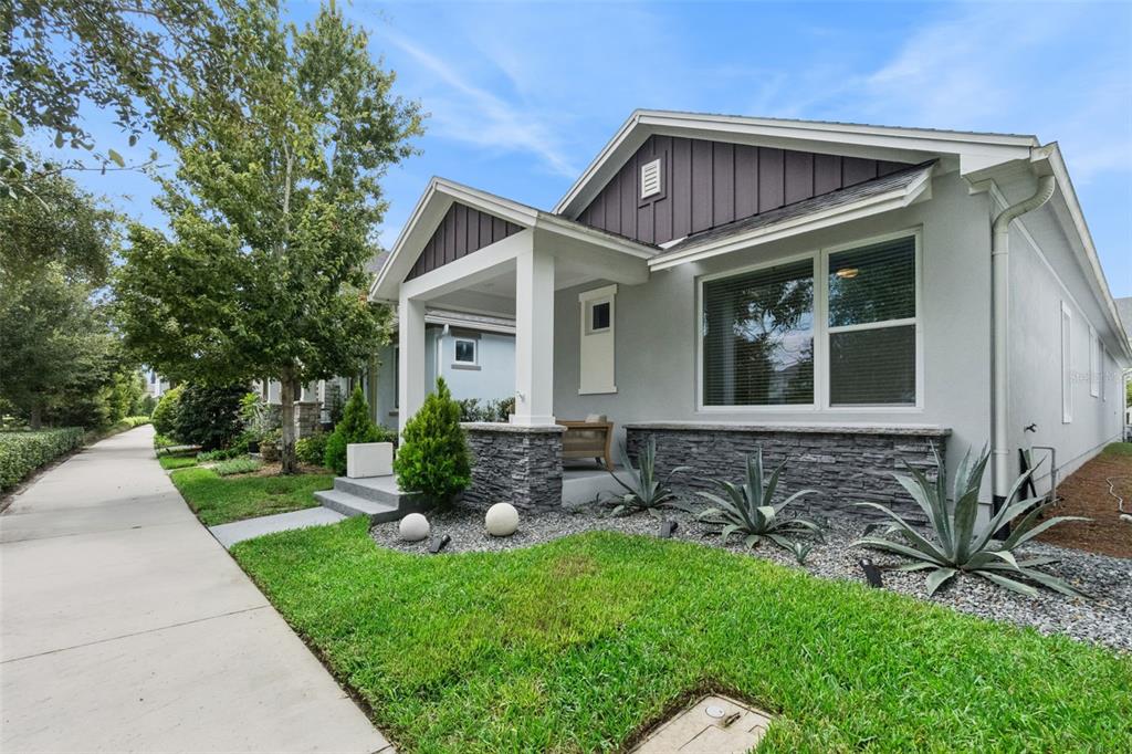 A single-story house with a gray stucco exterior, stone accents, and a covered front porch — 6935 HIGGS ALLEY, ORLANDO, FL