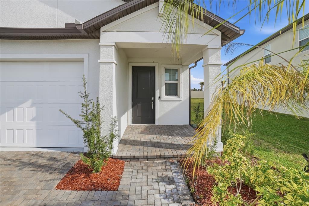 A paved walkway leads to the covered front porch and dark entry door of a house — 11534 72ND PLACE E, PALMETTO, FL