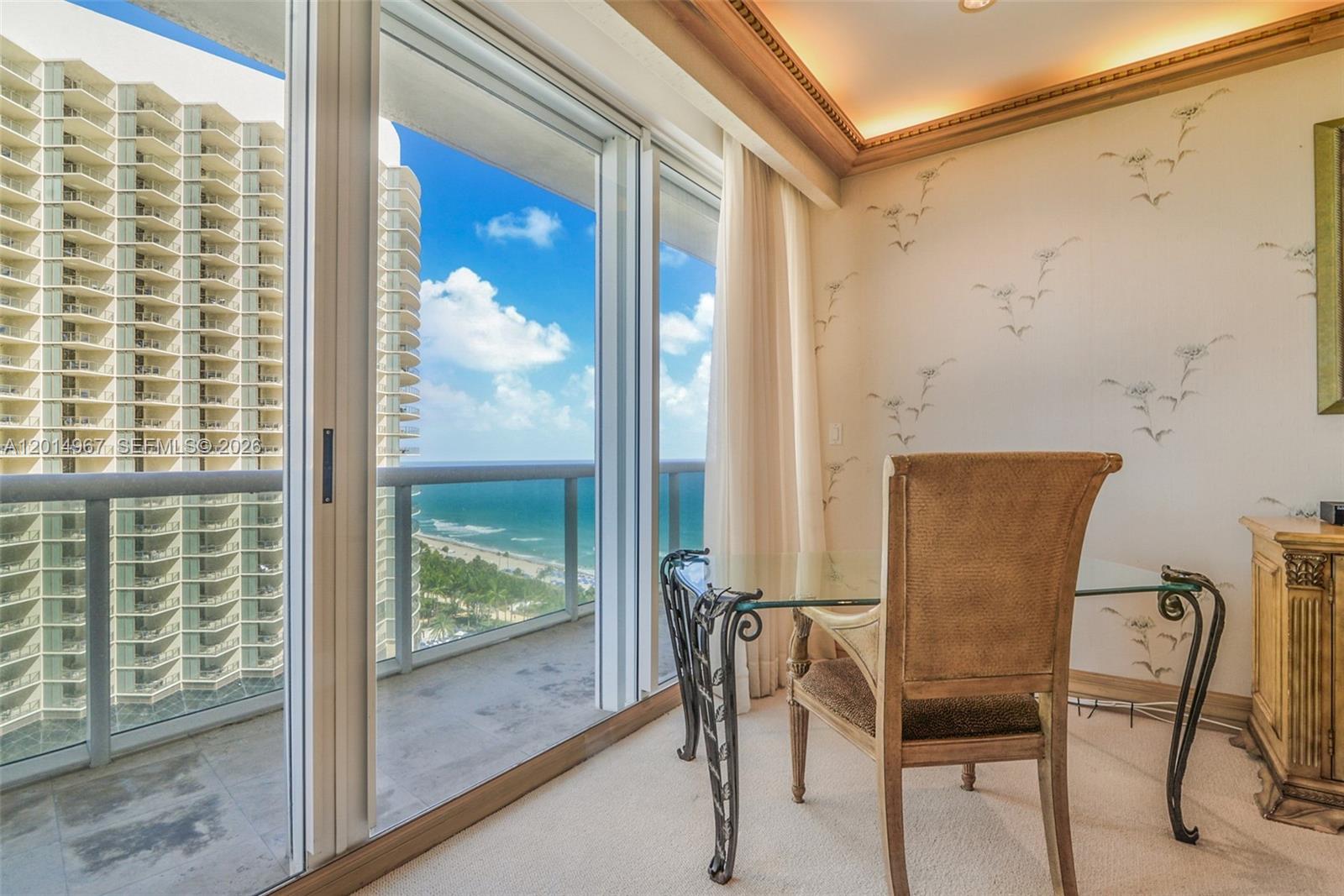 A room with a glass desk, patterned wallpaper, and a balcony overlooking the ocean — 9601 Collins Ave # 1502, Bal Harbour FL 33154, BAL HARBOUR, FL