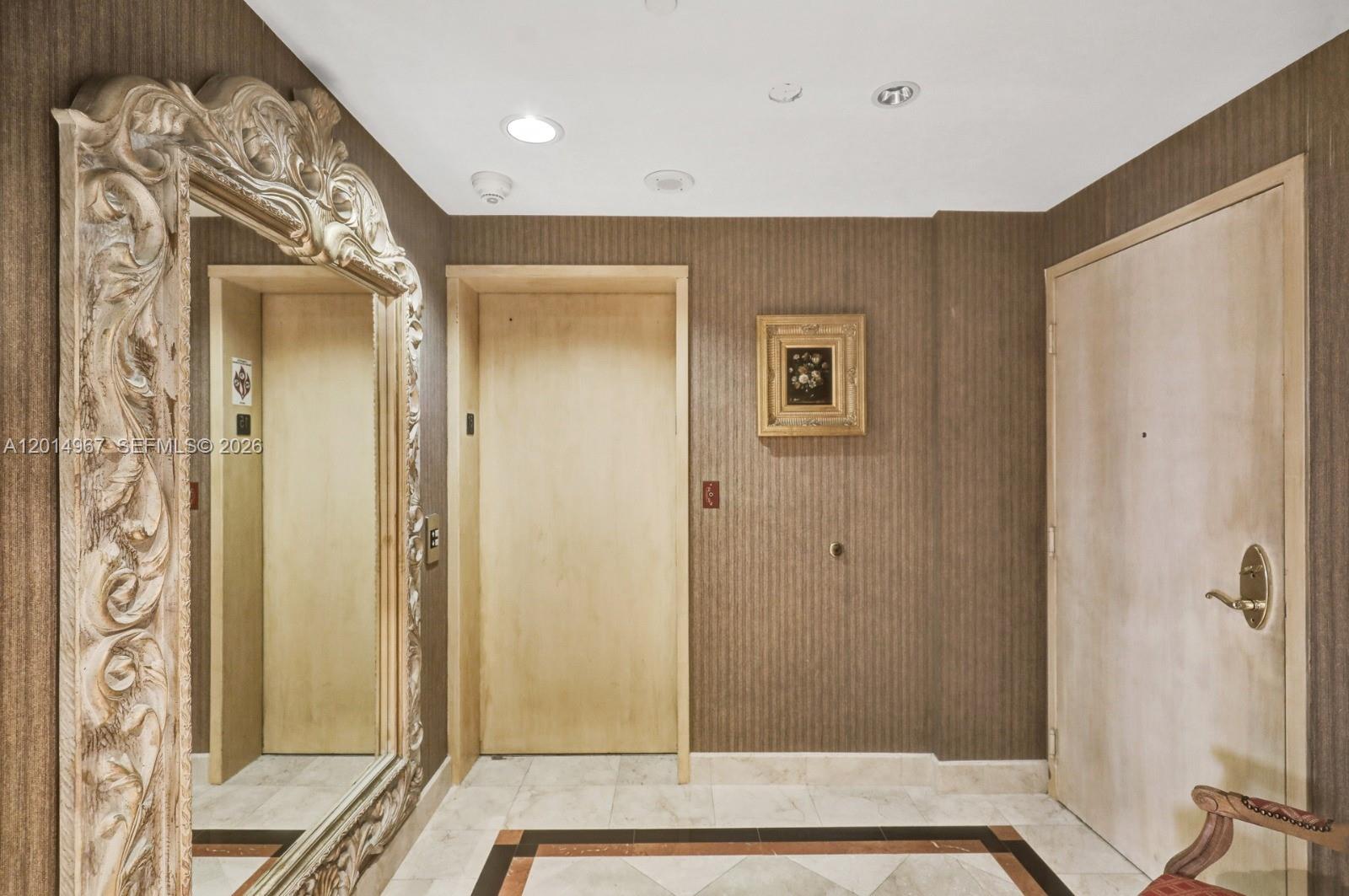 A hallway features a large ornate mirror, a light wood door, and textured brown wallpaper — 9601 Collins Ave # 1502, Bal Harbour FL 33154, BAL HARBOUR, FL