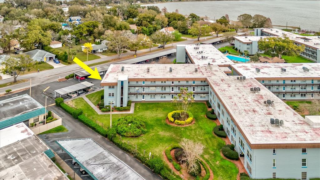 An aerial view shows a multi-story apartment building with a flat roof and parking carports — 333 LAKE HOWARD DR NW UNIT 314D, WINTER HAVEN, FL