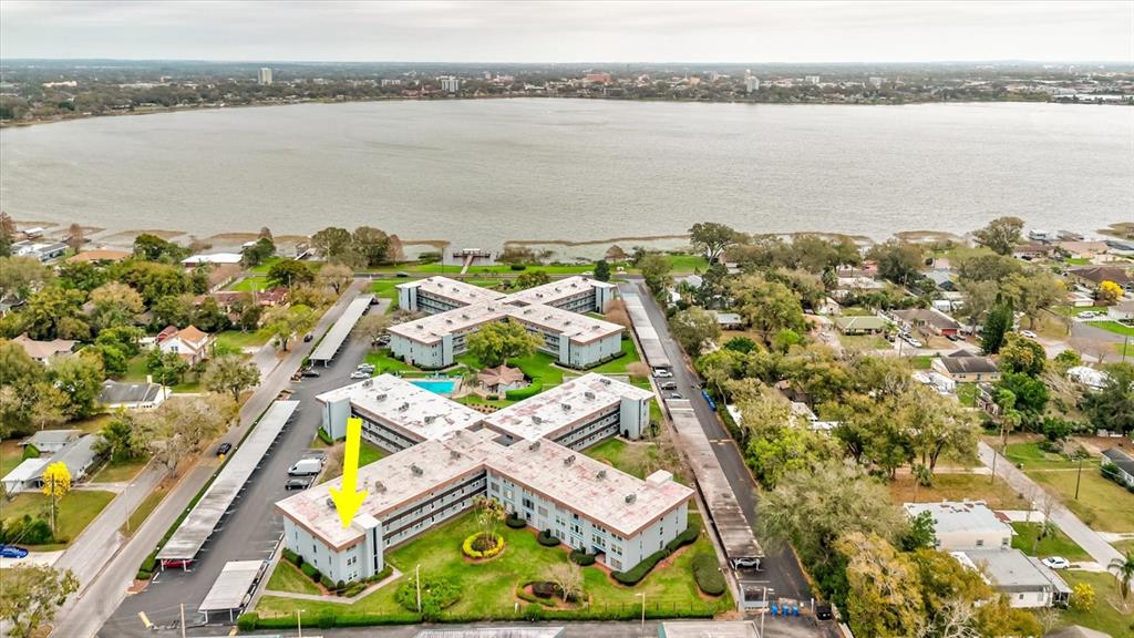 An aerial view shows two X-shaped apartment buildings near a large lake — 333 LAKE HOWARD DR NW UNIT 314D, WINTER HAVEN, FL