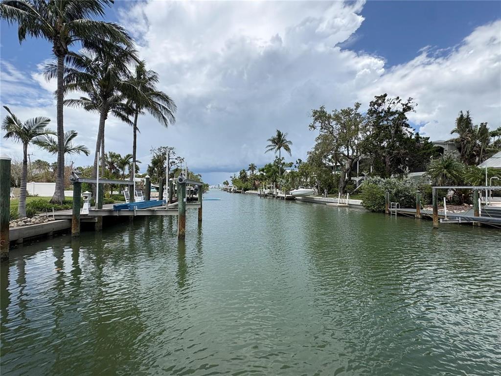 A view of a narrow canal lined with boat docks, palm trees, and residential properties — 3441 GULFMEAD DRIVE, SARASOTA, FL