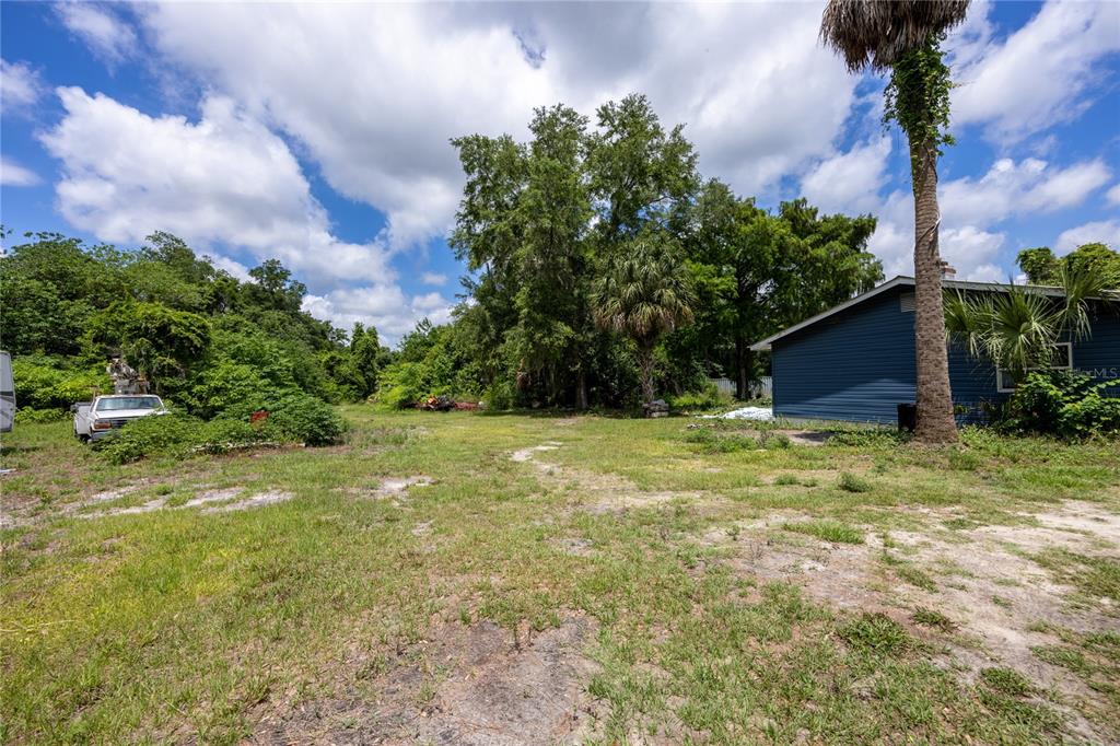 A grassy backyard features a blue house, a white truck, and several mature trees — 3728 N US HIGHWAY 441, OCALA, FL