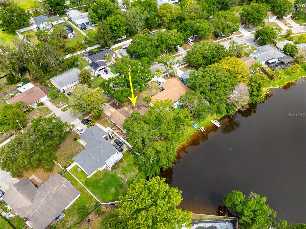 An aerial view shows a residential neighborhood with houses, trees, and a lake — 627 TIMBER BAY CIRCLE W, OLDSMAR, FL