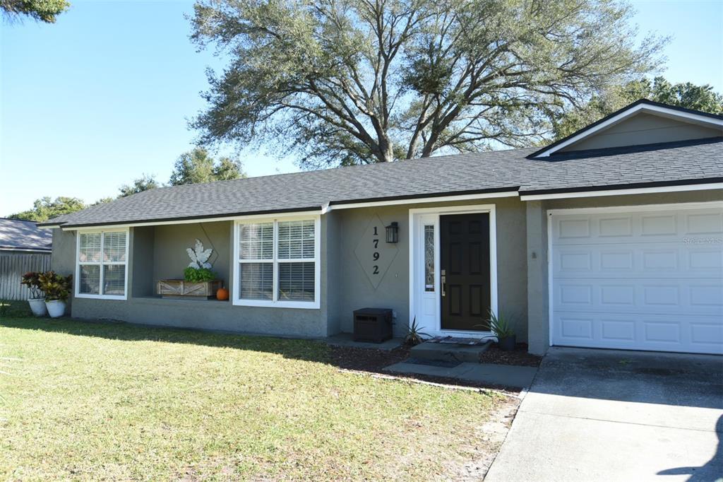 A single-story house with a gray exterior, dark front door, and a white garage door — 1792 PAM CIRCLE, ORLANDO, FL