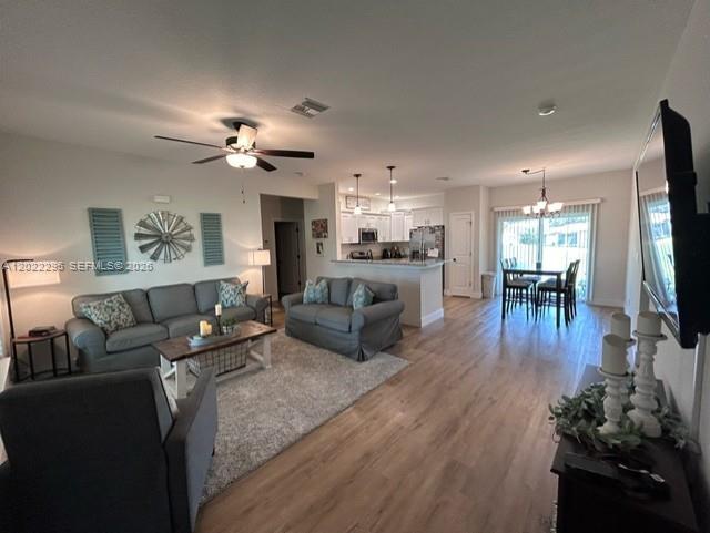 An open-concept living room and kitchen feature gray sofas, wood-look flooring, and a dining area — 109 Vale Cr, Sebring FL 33876, SEBRING, FL