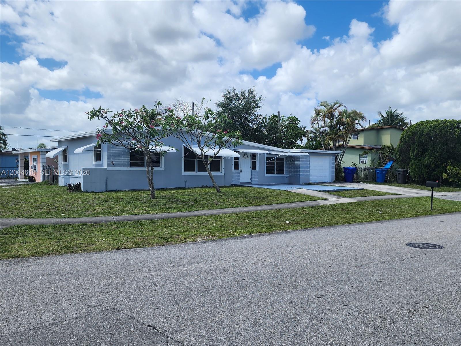 A single-story light blue house with a garage and metal awnings sits on a lawn — 4100 SW 36th St, West Park FL 33023, WEST PARK, FL
