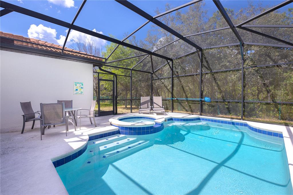 A screened-in patio features a swimming pool with an attached hot tub and outdoor seating — 2784 ROCCELLA COURT, KISSIMMEE, FL