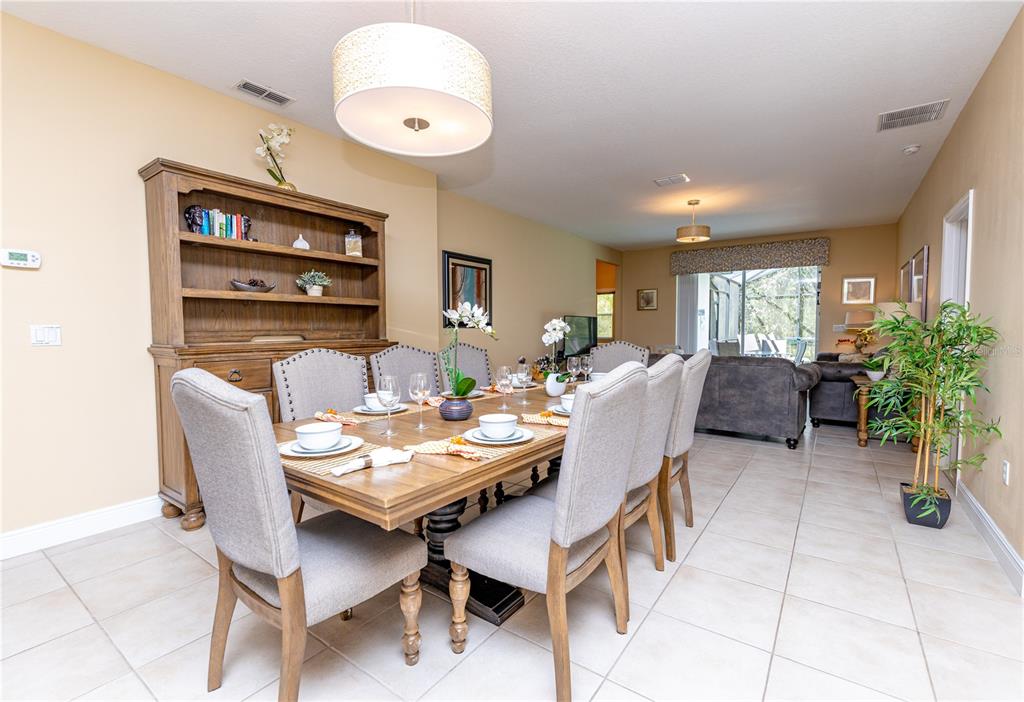 A dining room features a wooden table with upholstered chairs, a hutch, and tile flooring — 2784 ROCCELLA COURT, KISSIMMEE, FL