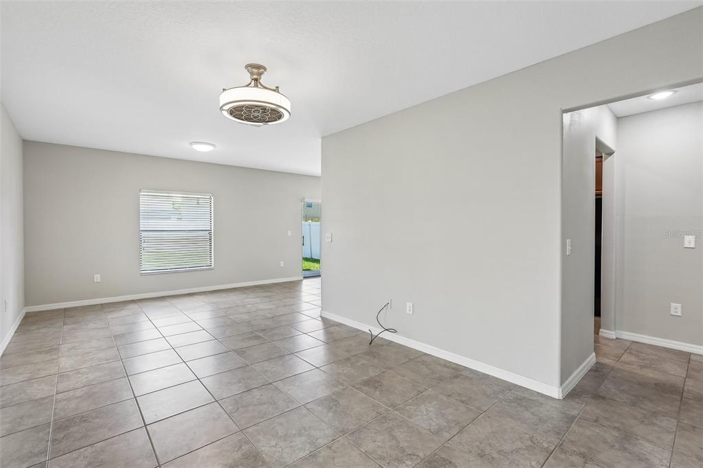 An open-concept living area features light gray walls, large neutral floor tiles, and a ceiling fan — 7414 CLARY SAGE AVENUE, TAMPA, FL