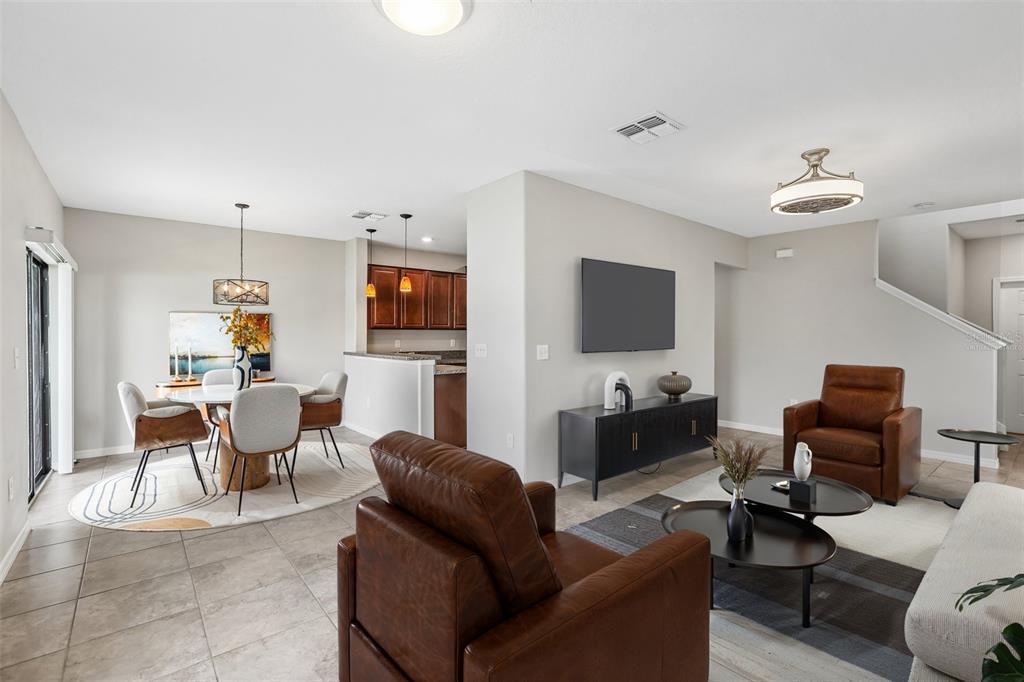An open-concept living and dining area features tile flooring, leather armchairs, and a kitchen view — 7414 CLARY SAGE AVENUE, TAMPA, FL