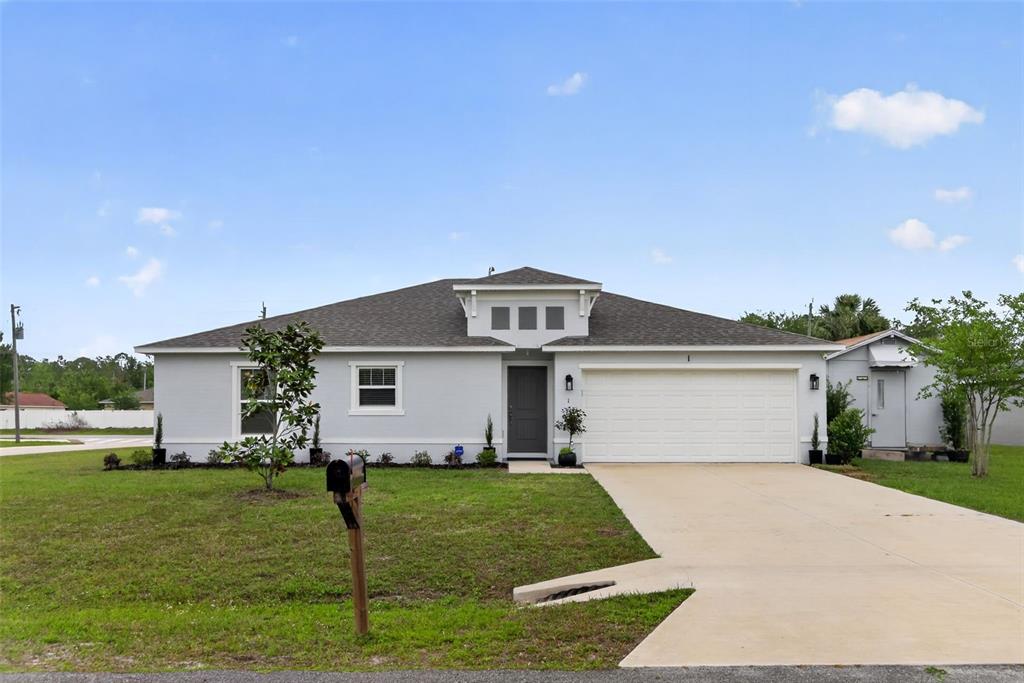 A single-story house with a gray exterior, a two-car garage, and a concrete driveway — 1 SERVICE TREE PLACE, PALM COAST, FL