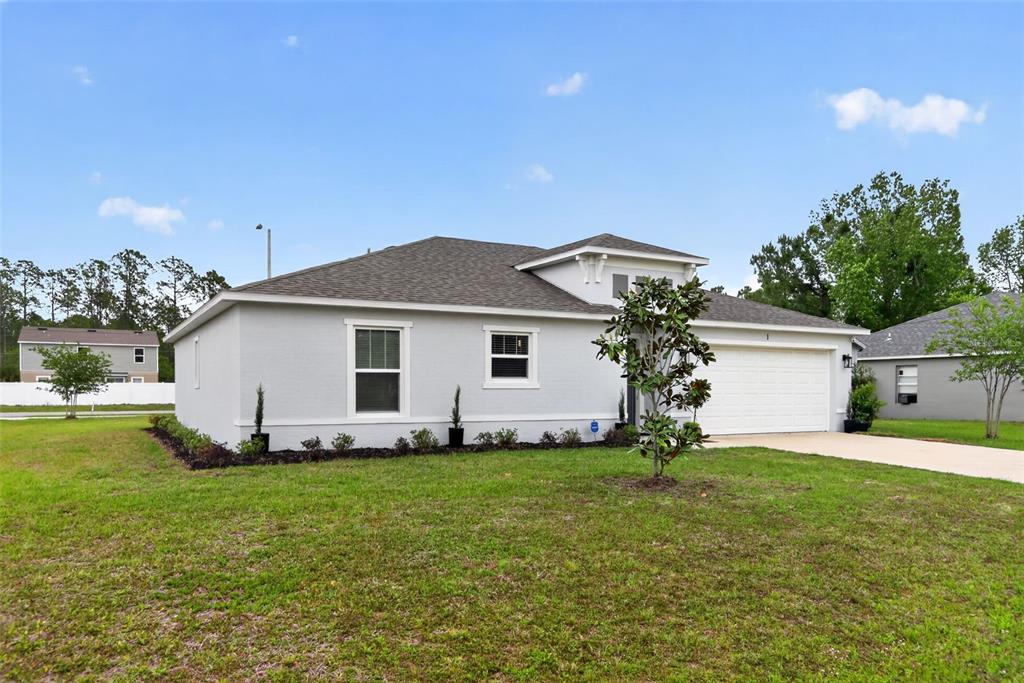 A light gray single-story house with a two-car garage and a landscaped front yard — 1 SERVICE TREE PLACE, PALM COAST, FL