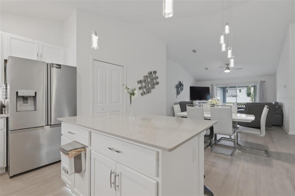 A kitchen island with white cabinets and quartz countertops sits before a dining area — 1 SERVICE TREE PLACE, PALM COAST, FL