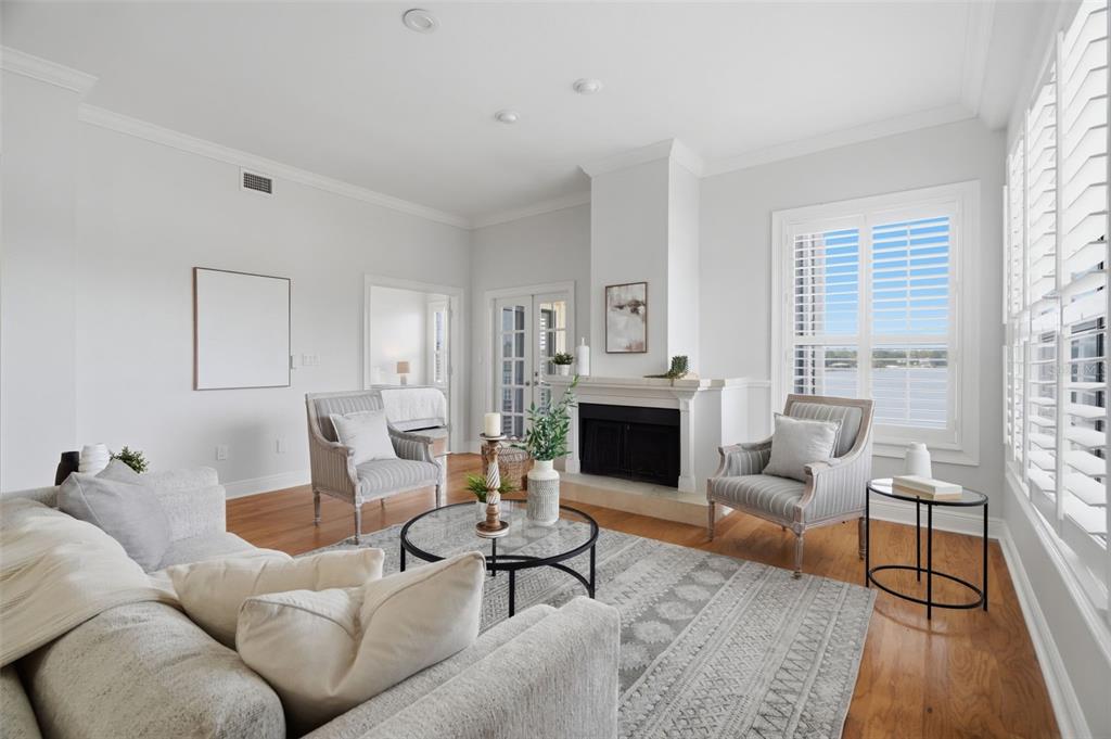 A bright living room features a fireplace, two armchairs, a sofa, and a water view — 3127 W SLIGH AVENUE UNIT 203B, TAMPA, FL