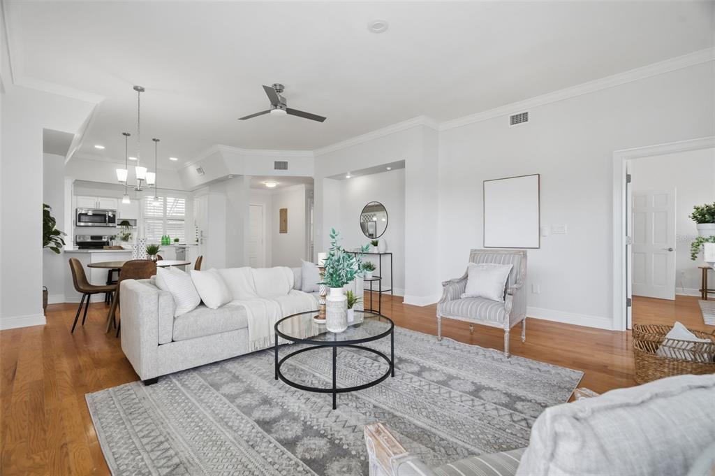 A bright living room features a grey sofa, patterned rug, and an open-concept kitchen area — 3127 W SLIGH AVENUE UNIT 203B, TAMPA, FL