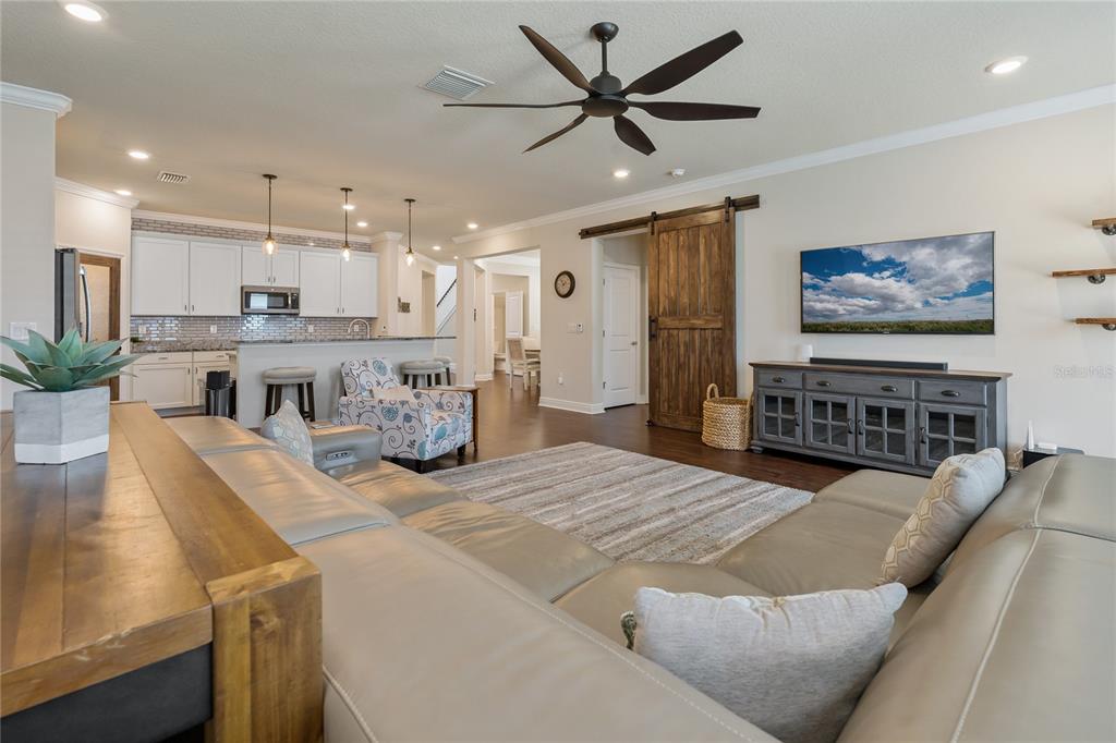A living room with a large sectional sofa, a barn door, and an open kitchen — 597 OZONA VILLAGE DRIVE, PALM HARBOR, FL