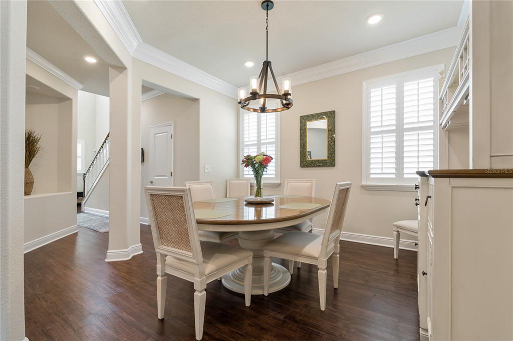 A dining room features a round wooden table, white chairs, and a dark wood floor — 597 OZONA VILLAGE DRIVE, PALM HARBOR, FL