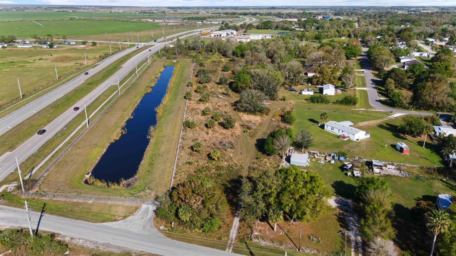 An aerial view shows a rectangular pond next to a highway and residential properties — 0 NE 60th & 64th Avenue, Okeechobee FL 34974, OKEECHOBEE, FL